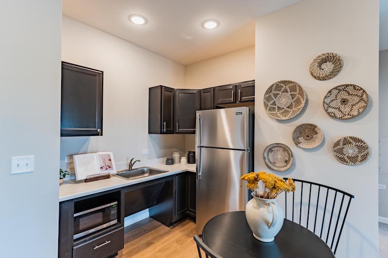 A modern kitchen with dark cabinetry, stainless steel appliances, and decorative elements on the wall.