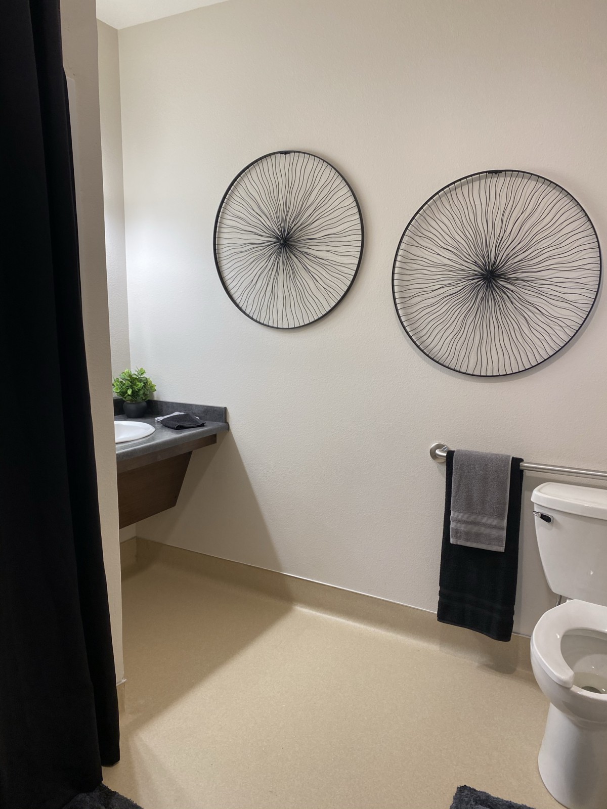 A modern bathroom featuring minimalist decor with two circular wall artworks, a sink, and neatly arranged towels.