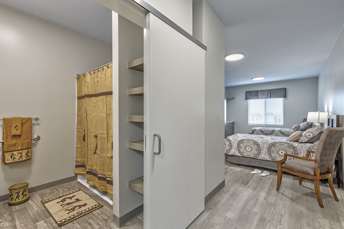 A modern, minimalist bedroom with a sliding door and built-in shelving unit.