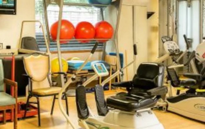 A well-equipped gym room with various exercise machines and fitness balls.
