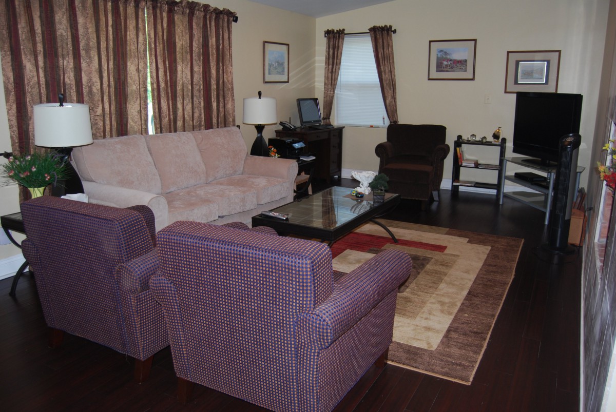 A cozy living room with a sofa, armchair, and coffee table, complemented by warm-toned curtains and decor.