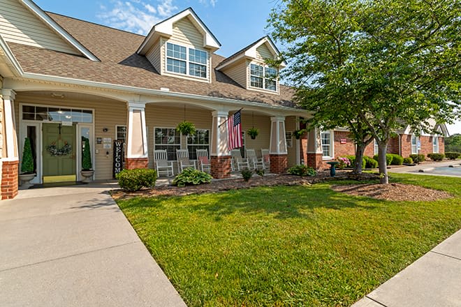 A suburban house with a well-maintained lawn and front porch on a sunny day.