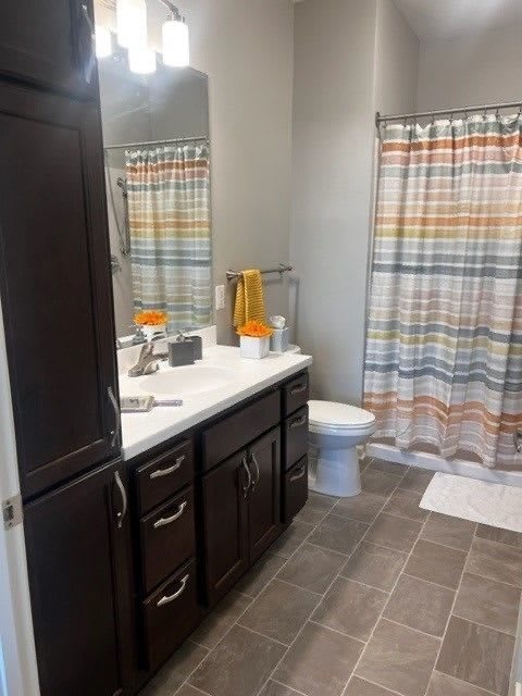 A modern bathroom with a sink, toilet, and colorful striped shower curtain.