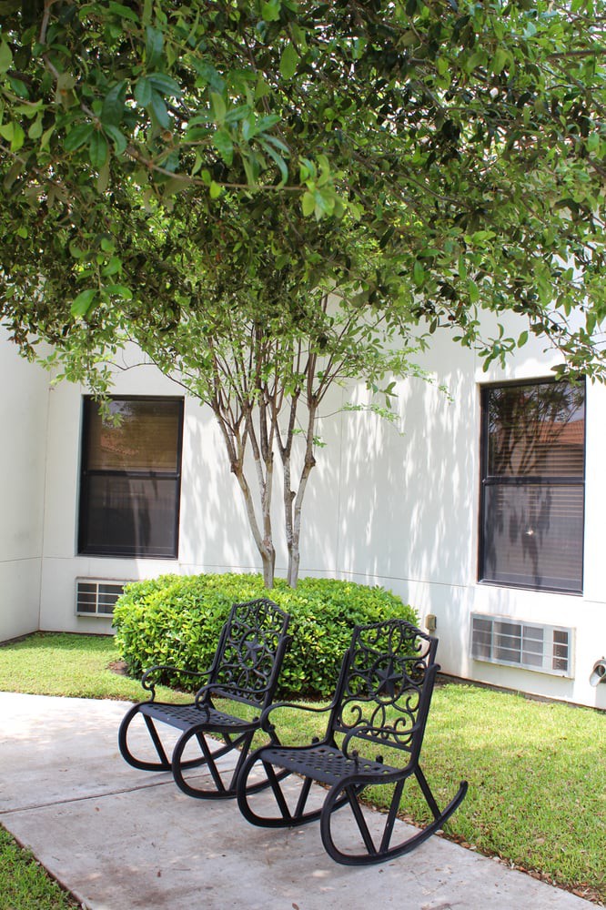 A peaceful outdoor area with benches under a tree near a building.
