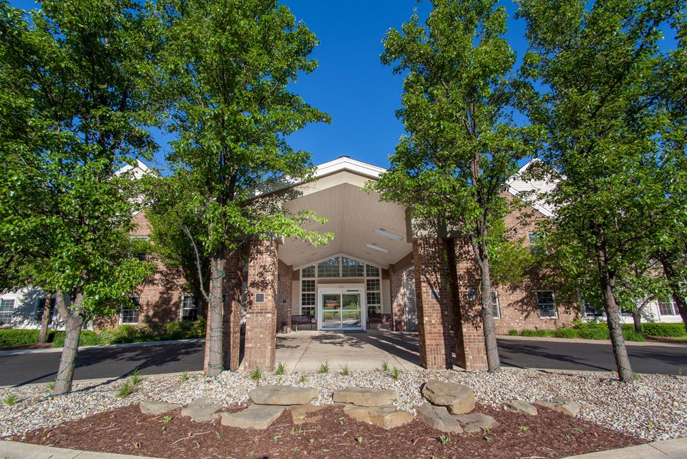 A building entrance surrounded by trees and landscaping.
