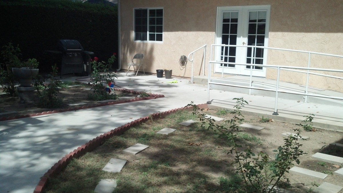 A backyard patio with a garden pathway leading to the house.
