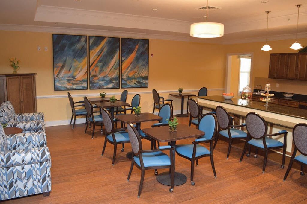 A dining area with multiple tables and chairs, decorated with artwork on the wall.