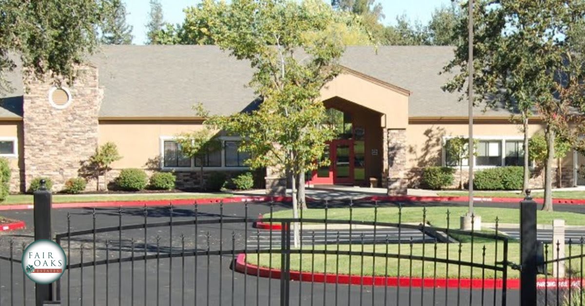 A suburban house with a neatly landscaped yard and a fenced driveway.