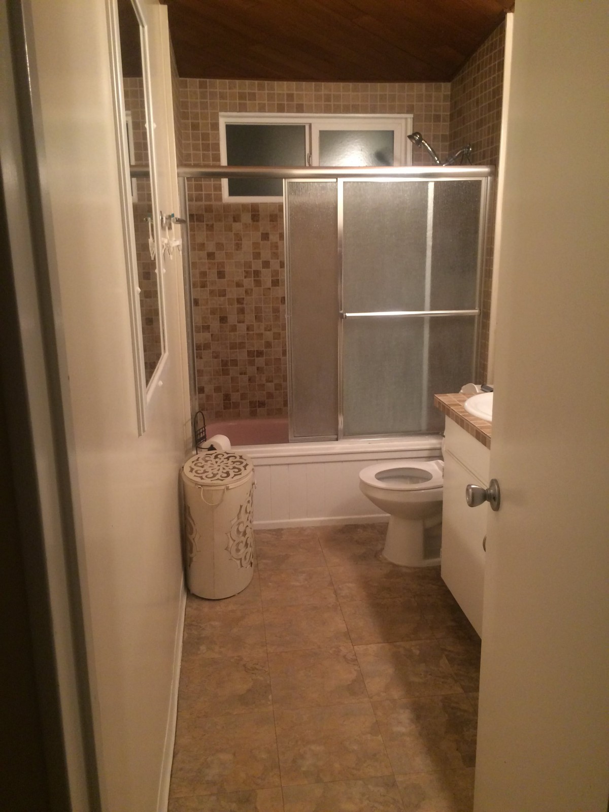 A compact bathroom with a shower, toilet, and vanity.