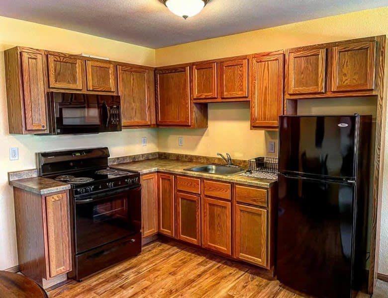 A modern kitchen with wooden cabinets and black appliances.