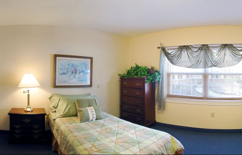 A cozy bedroom with a single bed, window, and dresser.