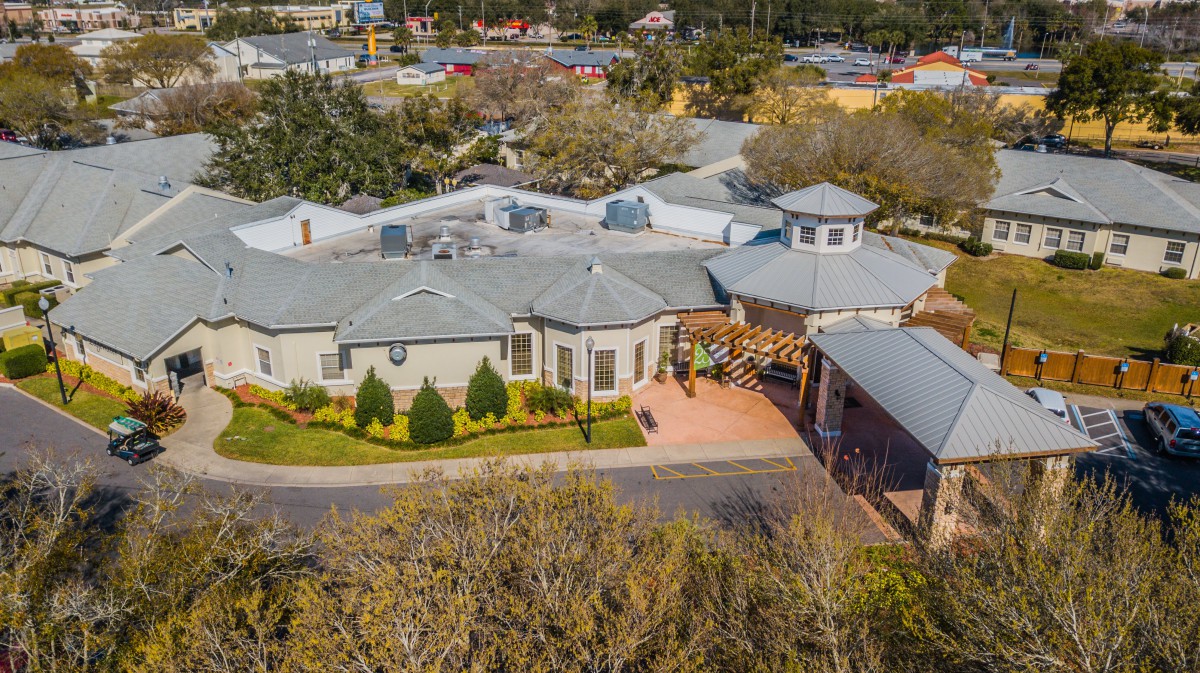 Aerial view of a suburban residential house surrounded by trees and a driveway.