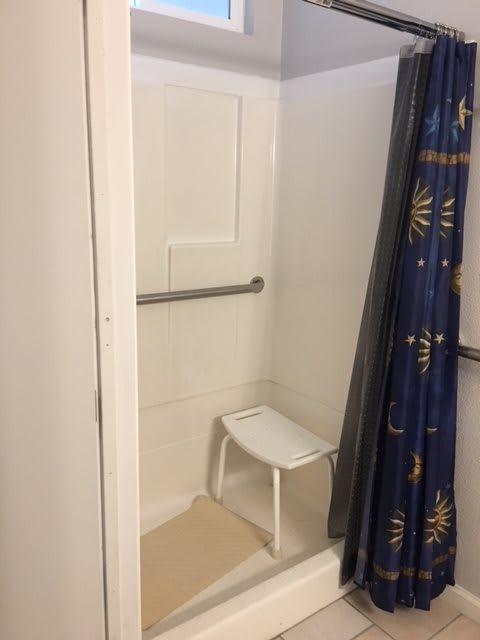 An accessible shower with a grab bar and a shower seat.