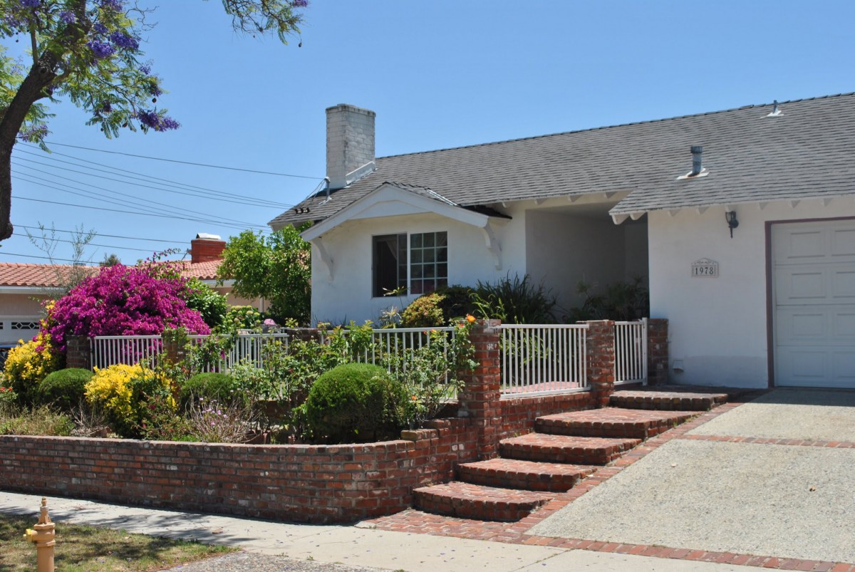 A charming suburban home with a well-maintained garden and brick steps leading to the entrance.