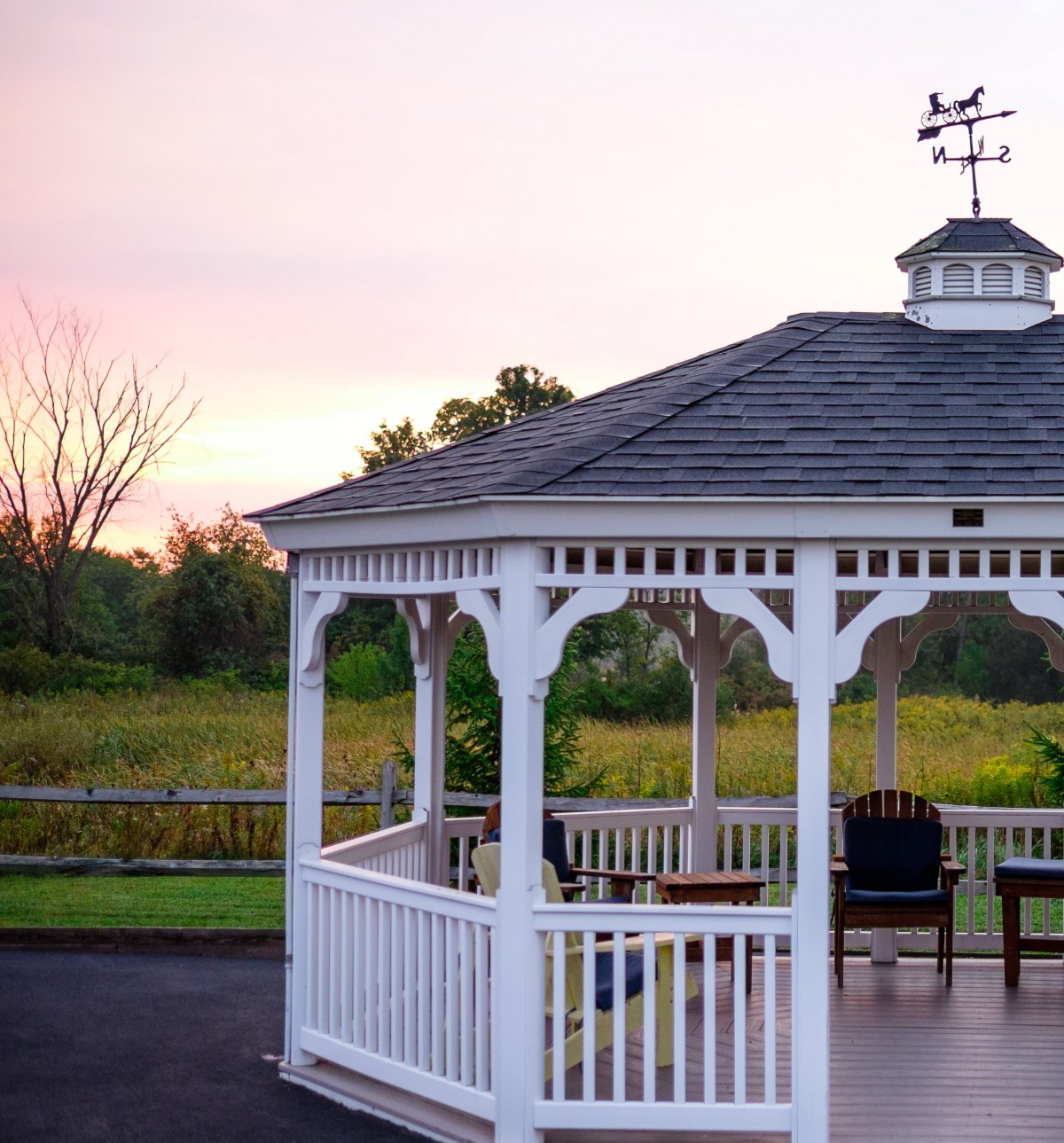 A serene gazebo sits amidst a picturesque landscape at sunset.