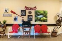 A cozy waiting room with red chairs and canoe-themed decor on the wall.