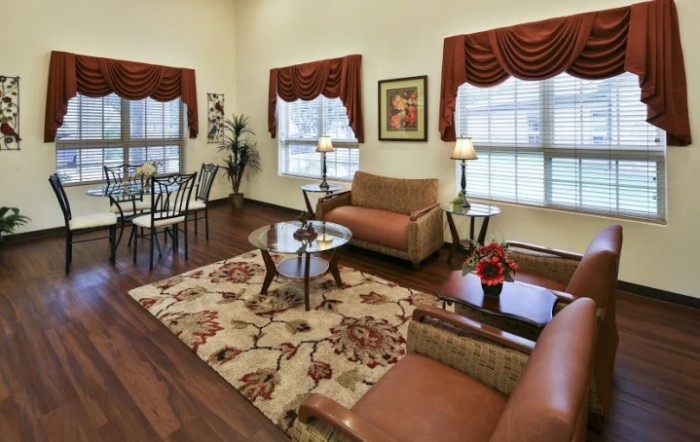 A cozy living room with a sofa, coffee table, and dining area featuring warm decor and wooden flooring.