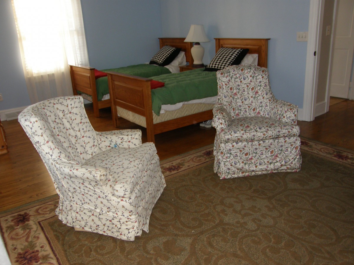 A cozy bedroom with two upholstered chairs and a wooden bed, showcasing classic home decor.