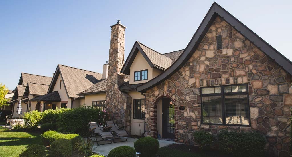 A charming stone house with a prominent chimney and well-maintained landscaping.
