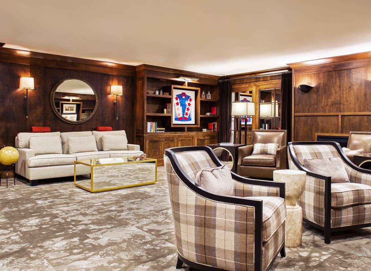 A luxurious living room featuring plaid chairs, a modern sofa, and elegant wooden bookshelves.