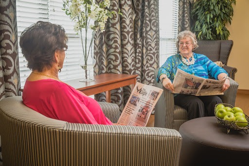Two women engaged in a pleasant conversation while reading magazines in a cozy indoor setting.