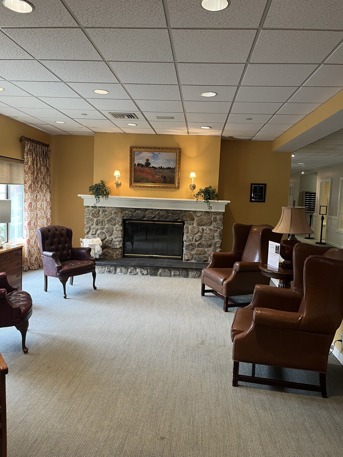 A cozy living room with comfortable armchairs arranged around a stone fireplace, complemented by warm lighting and tasteful decor.