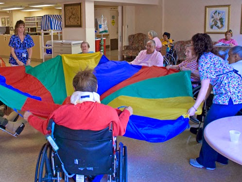 Seniors engaging in a fun parachute activity at a care facility.
