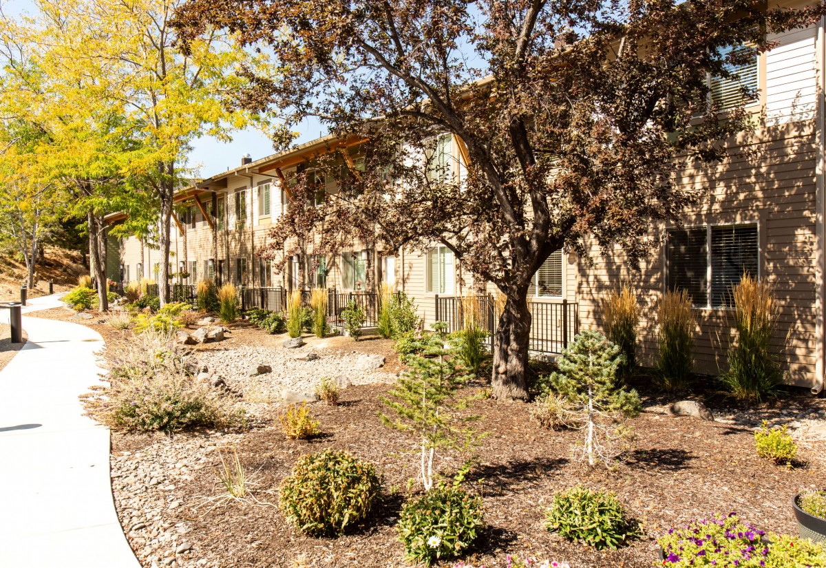 A residential apartment building surrounded by landscaped gardens on a sunny day.