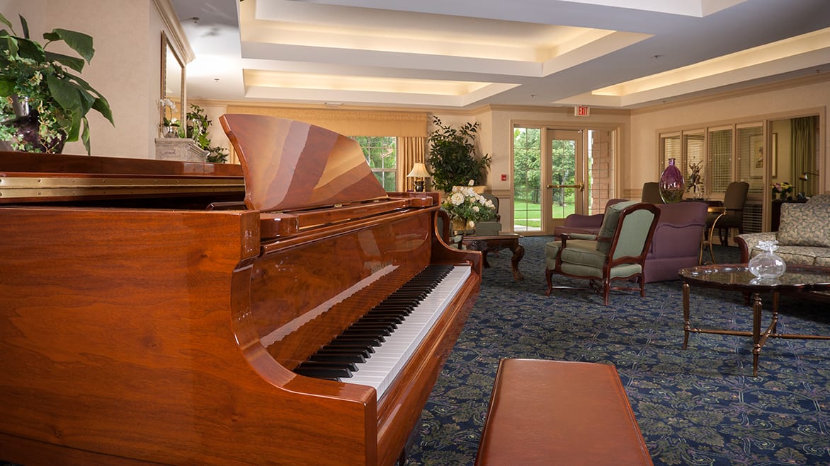 A cozy living room featuring a grand piano and ample natural light.