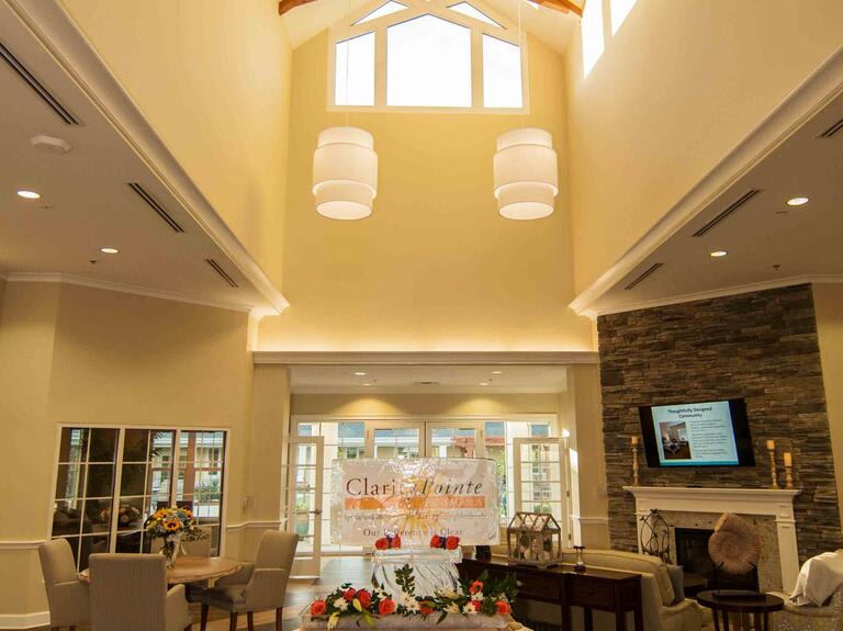 A spacious living room with high ceilings, elegant lighting fixtures, and a cozy fireplace.