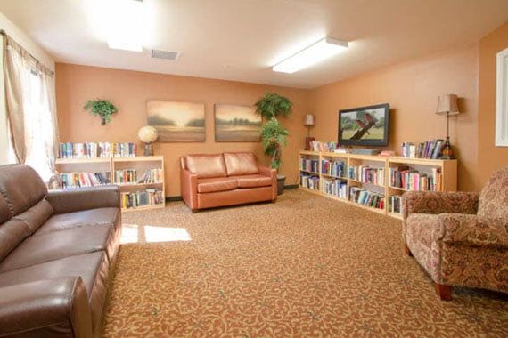 A cozy library room with sofas and bookshelves along the walls.