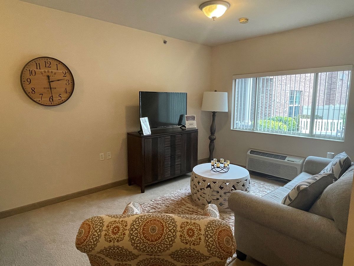 A cozy living room with a sofa, TV, and a coffee table near a large window.