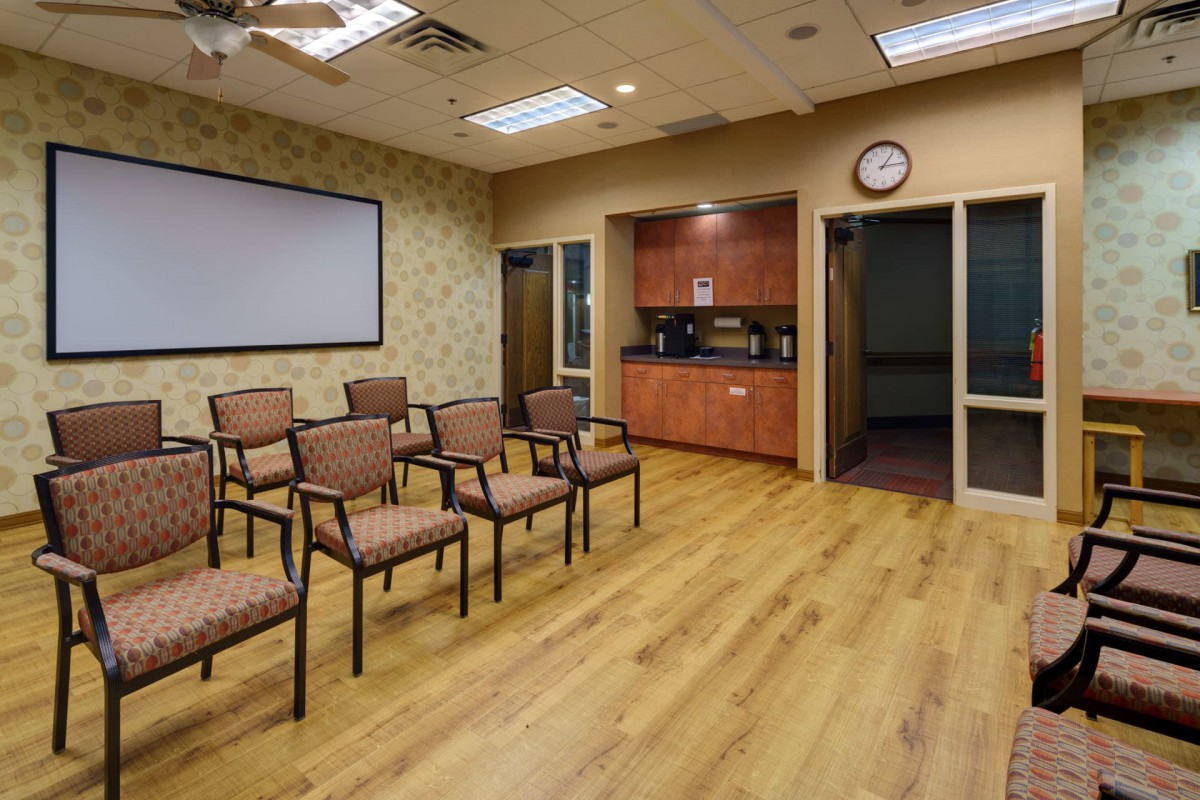 A quiet office waiting room with rows of chairs and a TV screen.