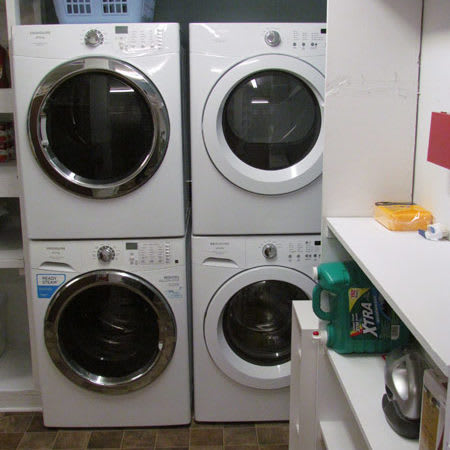 A well-organized laundry room with stacked washing machines and dryers.