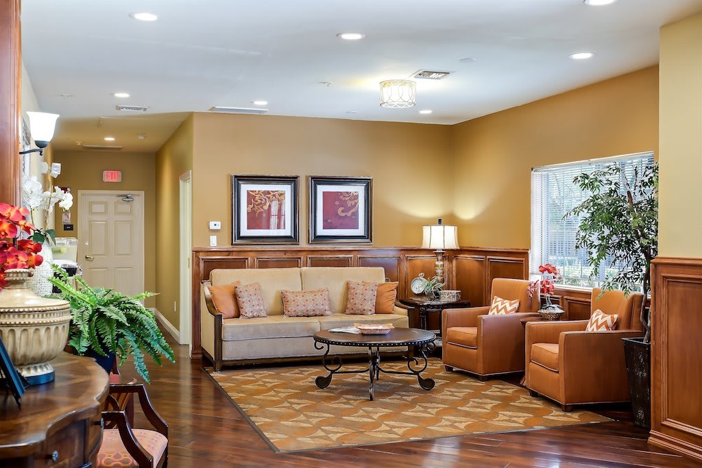 A cozy living room with warm colors, featuring a sofa, armchairs, and decorative artwork.