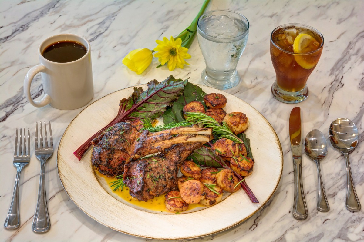 A delicious meal featuring steak and shrimp with vegetables, served alongside coffee and iced tea.
