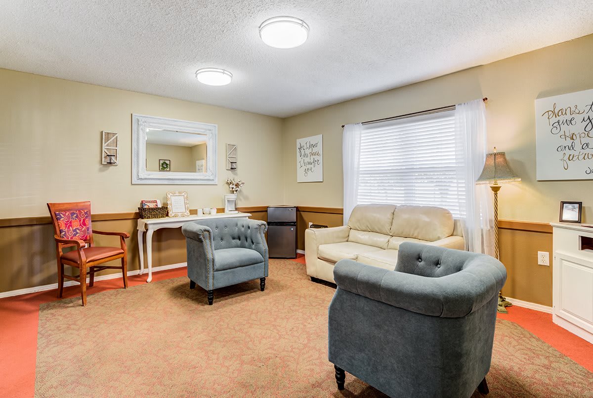 A cozy living room with armchairs and a sofa, highlighted by a large mirror and soft lighting.