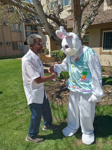 A cheerful interaction between a man and the Easter Bunny in a sunny outdoor setting.