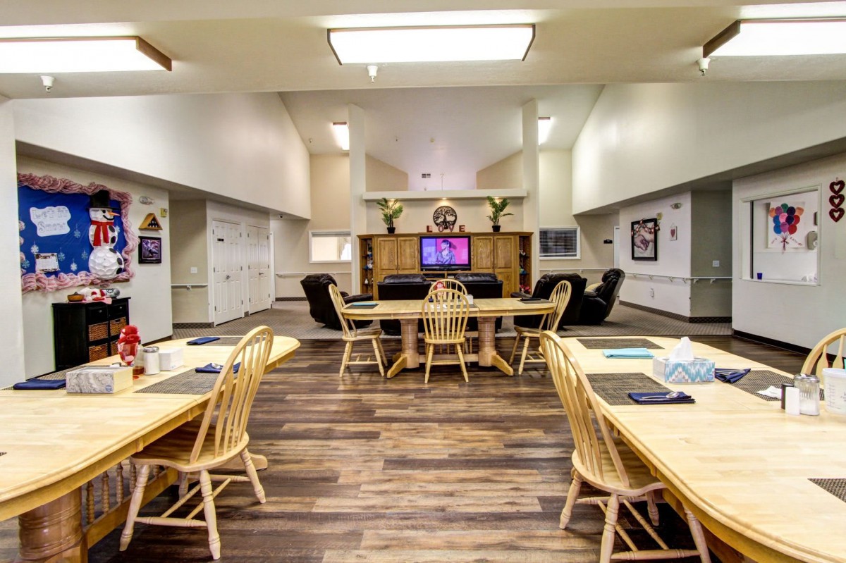 A spacious meeting room with wooden tables, chairs, and a television for presentations.