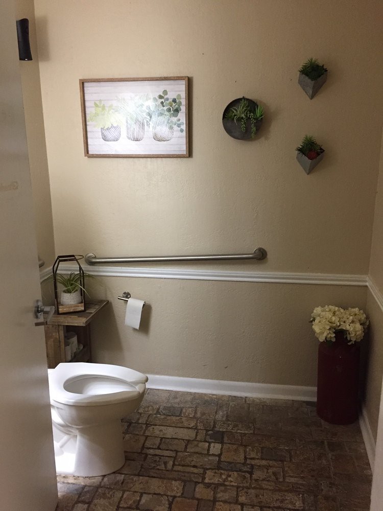 A neatly decorated bathroom with wall art and plants.