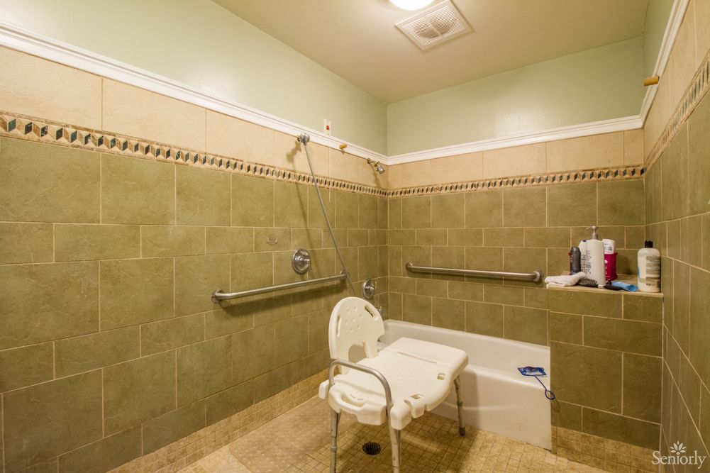 An accessible bathroom equipped with a shower chair and grab bars for safety.