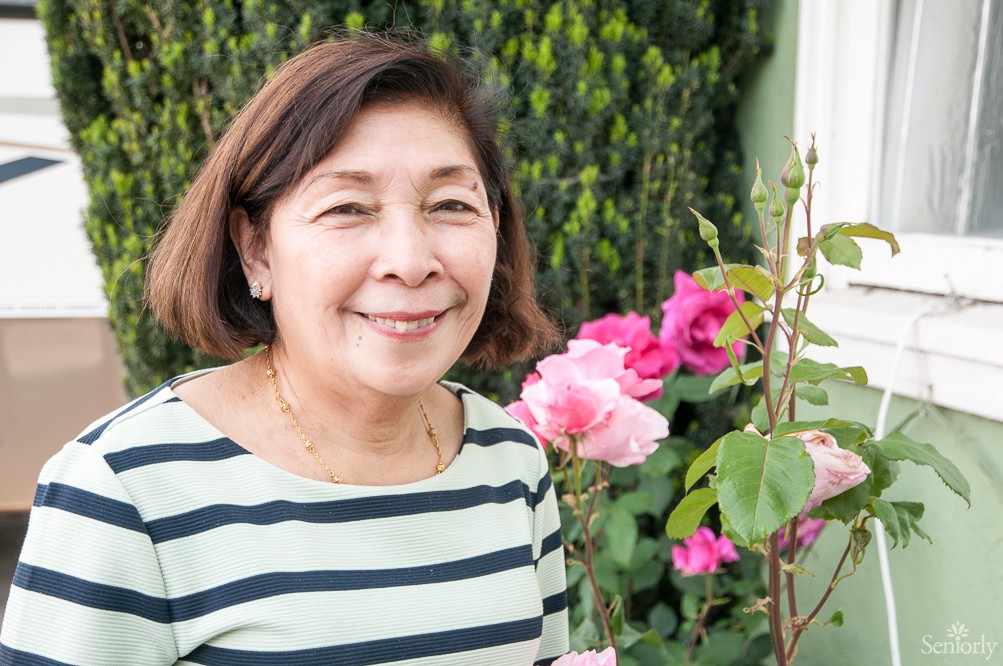 A woman smiling in a garden with flowers.