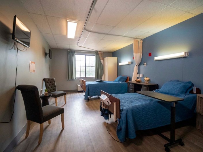 A hospital room with two beds and basic amenities.
