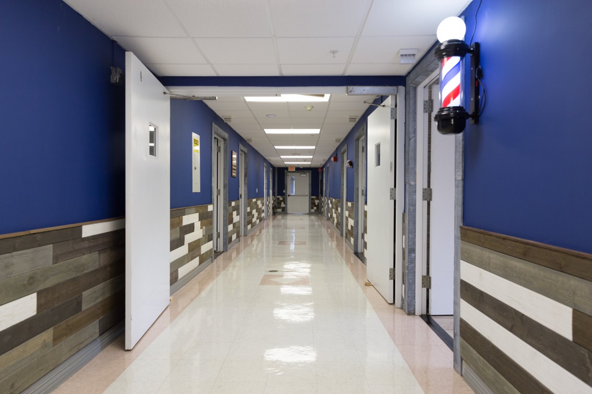 A brightly lit hallway with a row of doors and a barber pole on the wall.