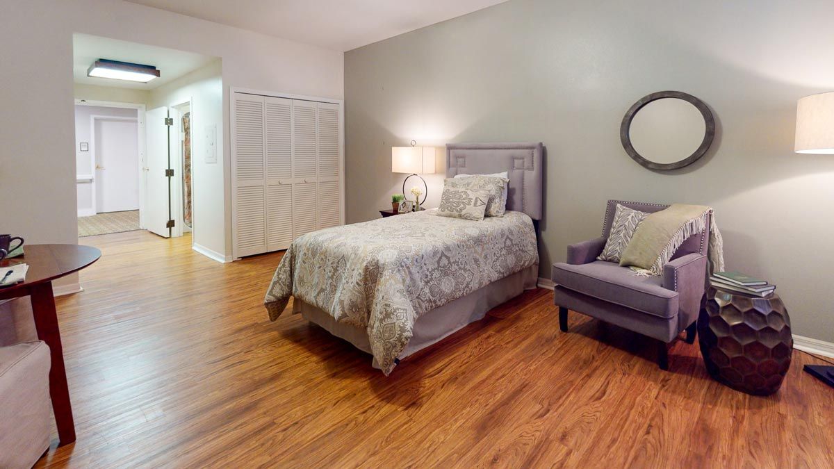 A cozy bedroom with a single bed, wooden flooring, and an armchair.