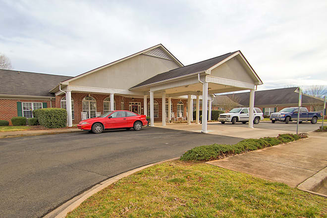A residential building with cars parked in the driveway.