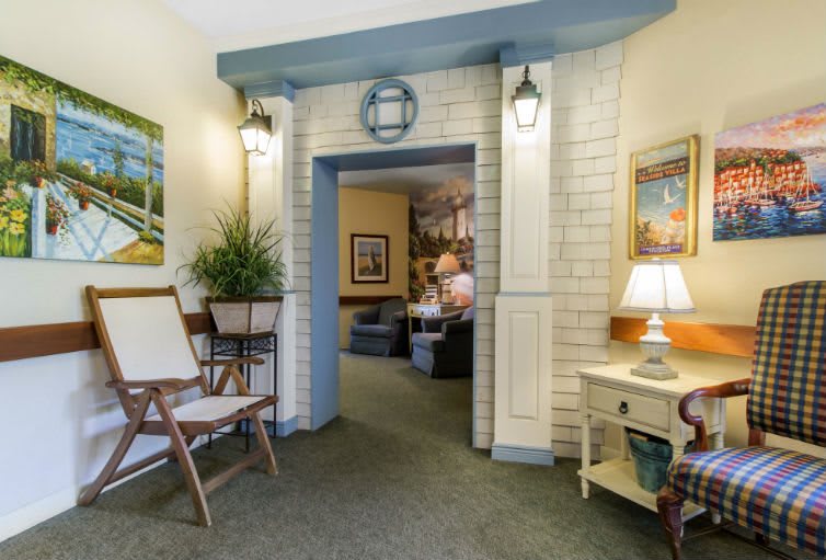 A cozy living room area with decorative elements, featuring a lamp, wall art, and indoor plants.