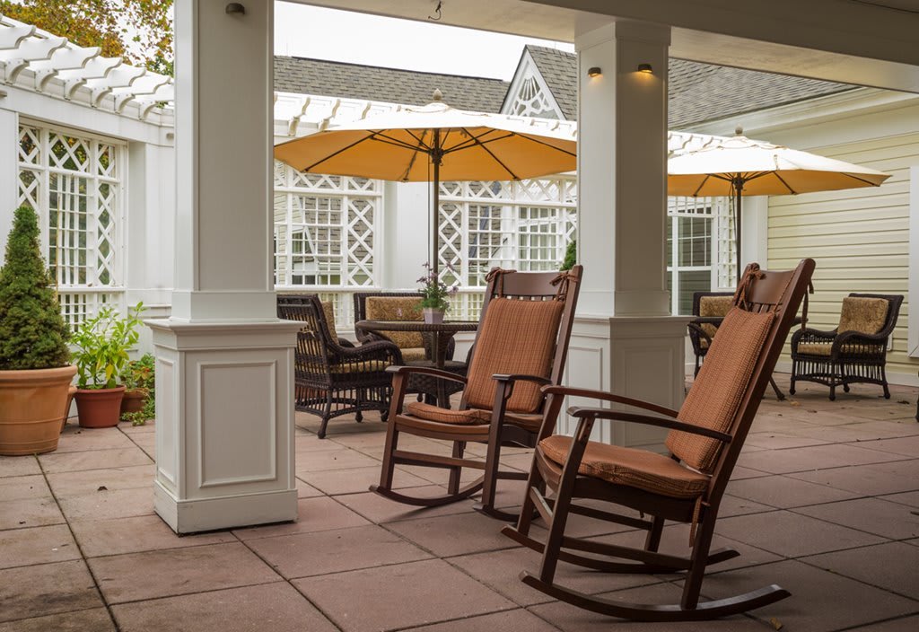 An inviting patio with rocking chairs and tables under umbrellas, perfect for relaxation.