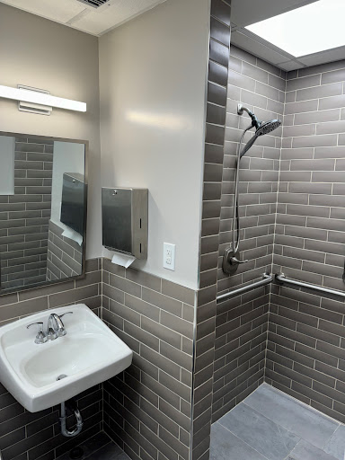 A modern bathroom featuring a shower, sink, and mirror with elegant tile work.