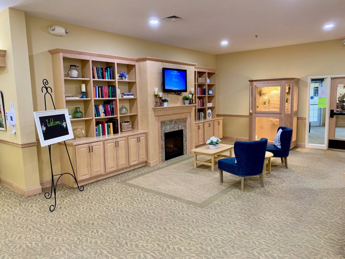 A cozy library seating area with bookshelves, a fireplace, and comfortable chairs.
